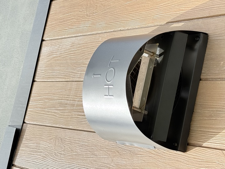 After — stained and marked stainless steel cowl on an external wall