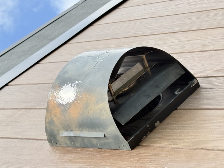 Before — stained and marked stainless steel cowl on an external wall
