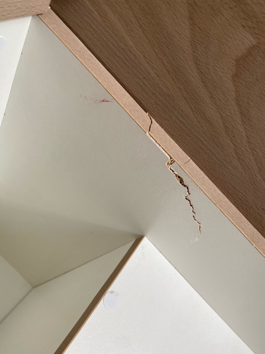 Before — chipped white panel edge inside a cupboard beside timber trim