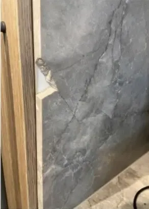 Before — chip on the edge of a dark stone wall panel