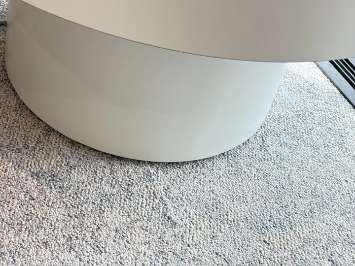 After: chipped bottom edge of a curved white seat base on carpet