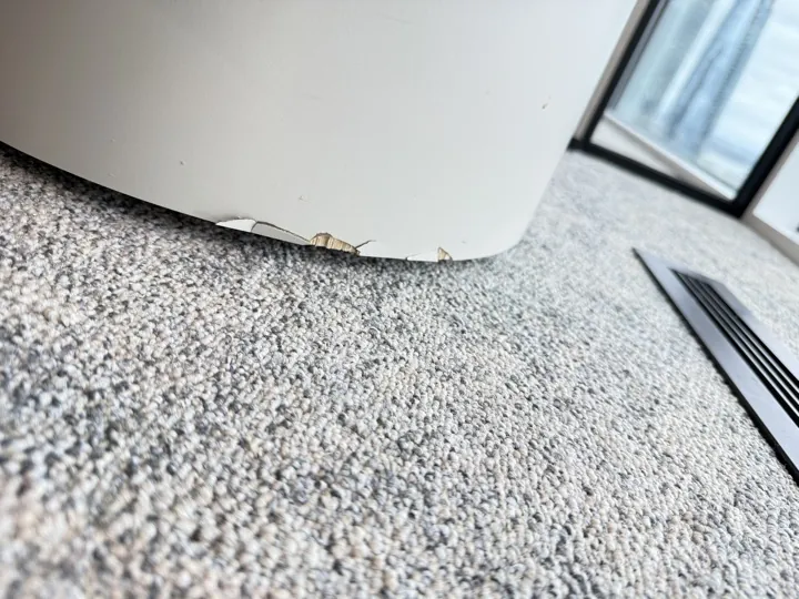 Before: chipped bottom edge of a curved white seat base on carpet
